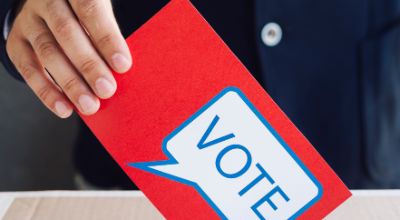 person-putting-red-ballot-election-box